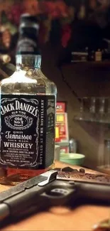 Whiskey bottle beside handgun on a bar counter.