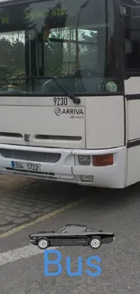 White bus parked on a city road with overcast skies.