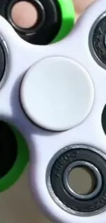 Close-up of a white fidget spinner with green accents.