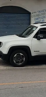 White SUV parked in front of a blue garage on a street.