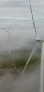 Wind turbines rising through mist in a calming landscape.