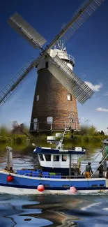 Mobile wallpaper of a windmill and boat by the water.