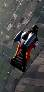 Person in wingsuit diving over vast landscape with fields below.