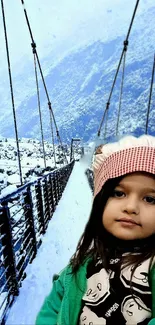 Child on a snowy bridge with mountain backdrop.