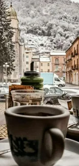 Steaming coffee with snowy village view.