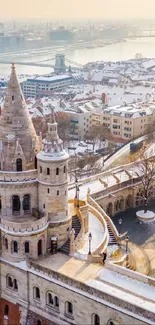 Snowy castle overlooking a serene winter cityscape with river.