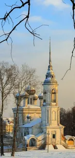 Snow-covered church under a blue sky in winter landscape wallpaper.