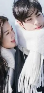 Couple in winter attire with scarves, set as phone wallpaper.