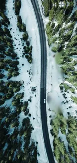 Aerial view of a winter road through a snowy forest, showcasing nature's beauty.