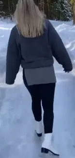 Woman walking on snowy path in forest.