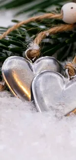 Metal heart decorations on snow-covered fir branches.