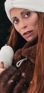 Woman holding heart-shaped snowball in winter scene.