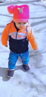 Child in vibrant winter clothing on snowy ground.