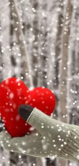 Red heart held in gloved hand amidst falling snow.