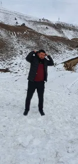 Man standing on snowy mountain under serene sky.