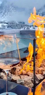 Glass by fire with snowy mountains backdrop in winter scene.