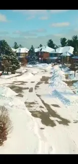 Snowy neighborhood scene with houses and trees under a clear blue sky.