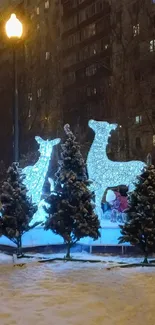 Illuminated deer sculptures with snow-covered trees at night.