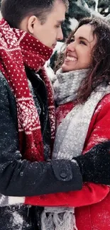 Couple embracing in snowy winter scene with red and gray coats