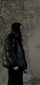 Person in winter coat standing against snow-covered trees.