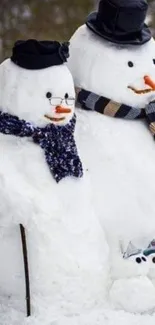 Snowman family wearing hats and scarves in winter setting.