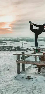 Person balances on wooden structure against sunrise in snowy landscape.