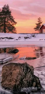 Winter sunset over frozen lake and snow-covered cabin.