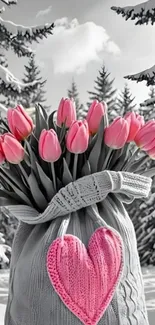 Bouquet of pink tulips in a gray knit bag with snow backdrop.