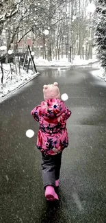 Child walking on a snowy road surrounded by winter trees.