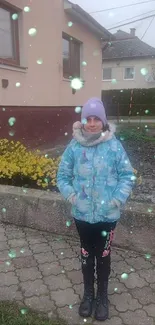 Mobile wallpaper of a child in snow with blue jacket and magical particles.