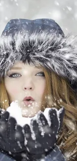 Woman in winter coat blowing snowflakes amid snowfall.