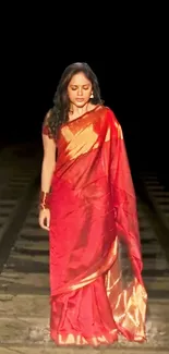 Elegant woman in red saree on a dark background.