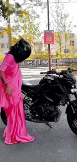 Woman in pink sari standing next to motorcycle.