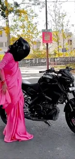 Woman in pink sari with motorcycle on a sunny street.