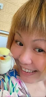 Woman smiles with a parrot on shoulder.