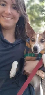 Smiling woman holding a dog in a park setting wallpaper.