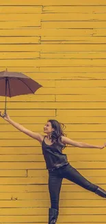 Woman with umbrella against yellow wall.