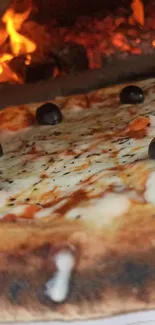 Wood-fired pizza with olives and a fiery background.