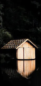 A rustic cabin reflects on a tranquil dark lake surrounded by forest.