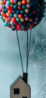 Colorful balloon lifting wooden house against rainy glass background.