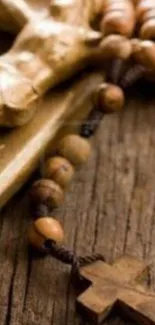 Wooden rosary with cross on rustic wood surface.