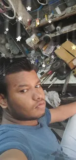 Person in blue shirt taking a selfie in a workshop environment.