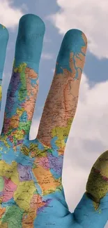 Hand with vibrant world map design against sky.