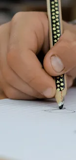 A hand writing with a pencil on lined paper, focused and detailed.