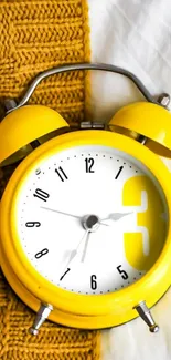 Yellow alarm clock on textured fabric background.