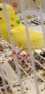 Yellow budgie in cage with colorful leaves.