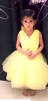 Child in a yellow dress against a dark curtain background.