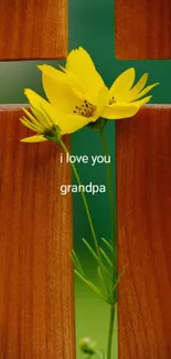 Yellow flower through a wooden cross with 'I love you grandpa' text.