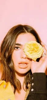 Woman with yellow rose against pastel pink background.