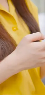 Person in yellow shirt focused on smartphone.